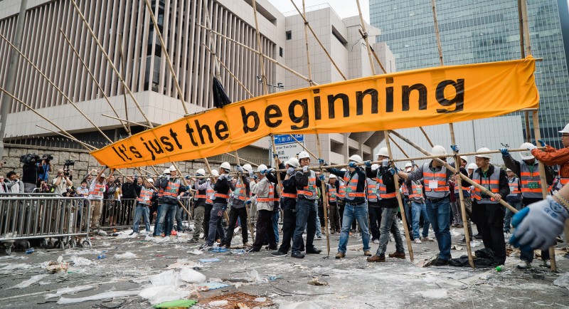 Workers take down a massive banner which reads This Is Just The Beginning.