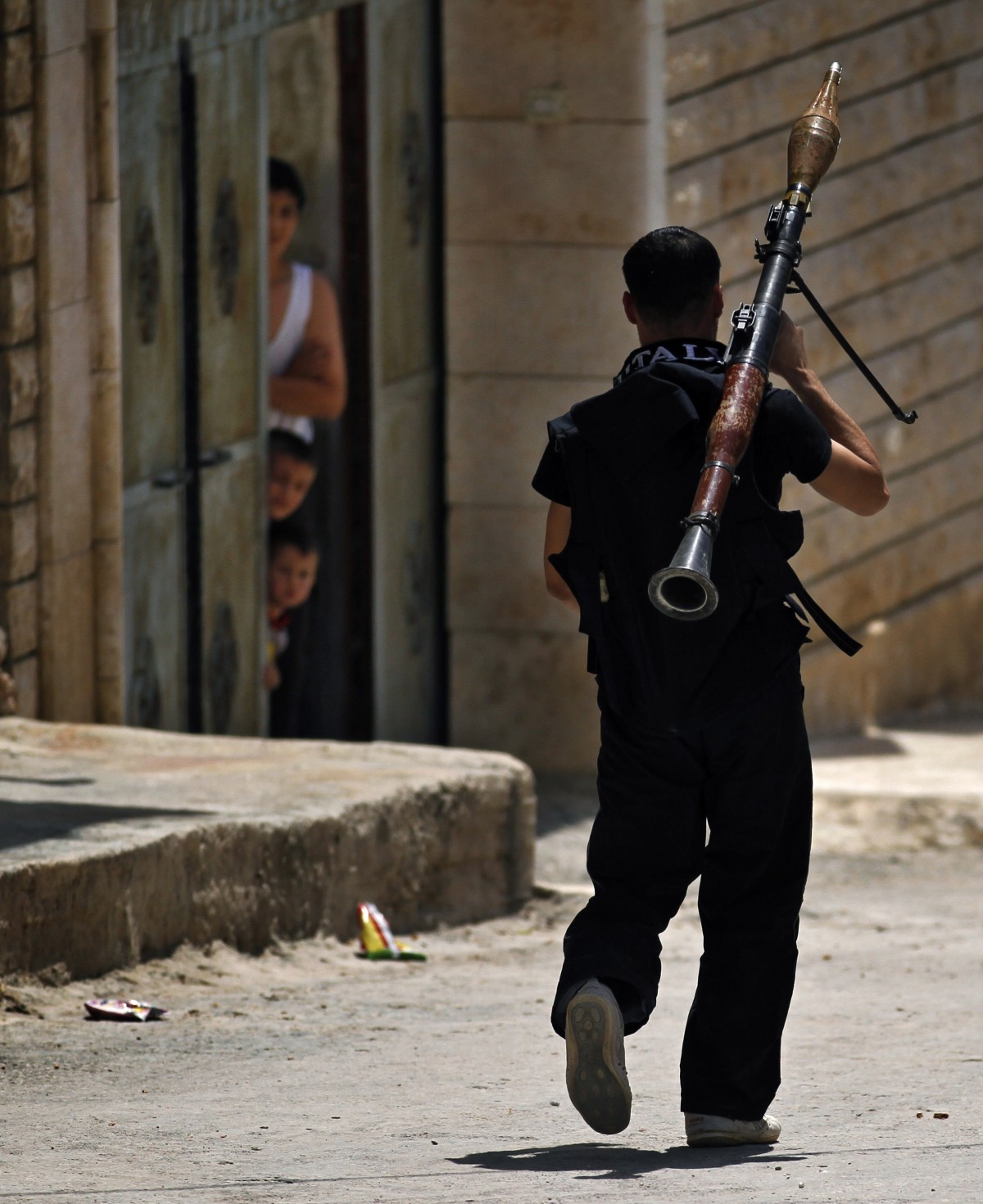 A Free Syrian Army fighter walks with a rocket launcher moments before clashing with Syrian troops near Idlib, Syria.(AP Photo/Khalil Hamra)