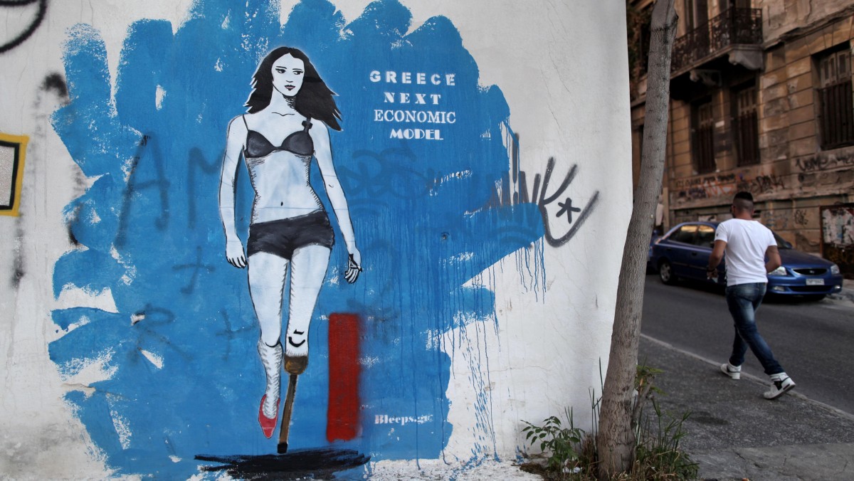 A man walks next a graffiti in central Athens on Tuesday, June 19, 2012. (AP Photo/Petros Giannakouris)