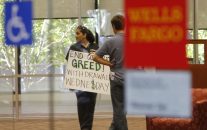 An Occupy San Diego protestor holds a sign urging bank withdrawals while waiting to close her account in a Wells Fargo bank branch Wednesday, Nov. 2, 2011 in downtown San Diego. (AP Photo/Lenny Ignelzi)