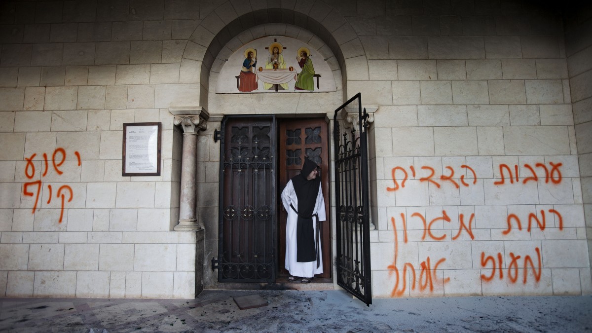 In this Sept. 4, 2012, file photo, a Catholic monk stands in a doorway of the Latrun Trappist Monastery where Israeli police say vandals spray-painted anti-Christian and pro-settler graffiti and set the monastery's door on fire, in Latrun, between Jerusalem and Tel Aviv, Israel. (AP Photo/Oded Balilty, File)