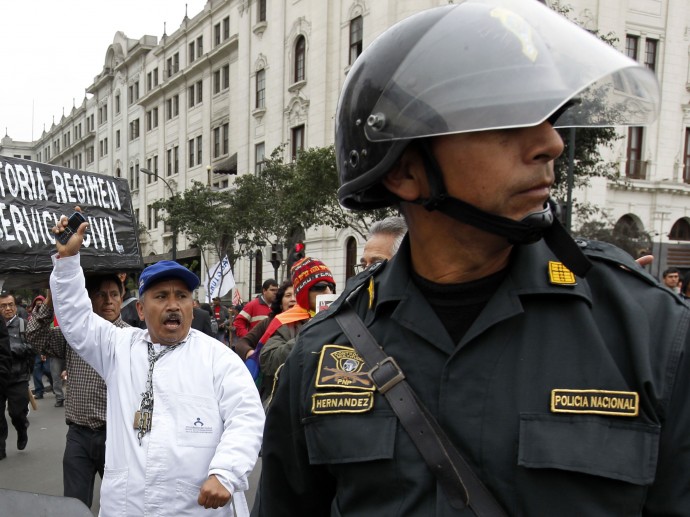 Workers carry a fake coffin as they are escorted by the police during a protest against the new civil service law that will require government employees to undergo work evaluations, in Lima, Peru, Thursday, July 4, 2013. After hours of debates and months of modifications, Peru's Congress approved the new civil service law with 59 votes in favor, 45 against and 3 abstentions. (AP Photo/Martin Mejia)