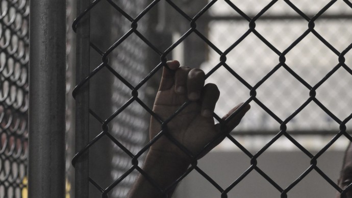 In this photo reviewed by a U.S. Department of Defense official, a Guantanamo detainee holds on to a fence inside the Camp 6 high-security detention facility on Guantanamo Bay U.S. Naval Base in Cuba, Tuesday April 27, 2010. (AP Photo/Michelle Shephard, Pool)