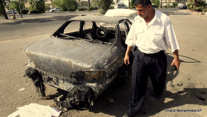 An Iraqi traffic policeman inspecting a car destroyed by a Blackwater security detail in al-Nisoor Square in Baghdad, Iraq.