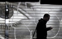 A man looks at his cell phone as he walks on the street.