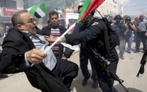 Palestinians protester is pushed by Israeli border policemen during a protest marking the Land Day in the West Bank village of Hawara near Nablus, Monday, March 30, 2015.