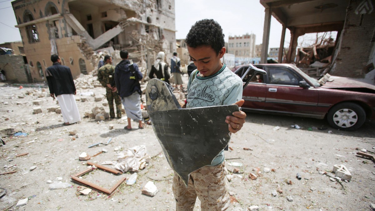 A Shiite rebel, known as a Houthi, holds up a fragment next to the rubble of a houses destroyed by a Saudi-led airstrike in Sanaa, Yemen, Friday, July 3, 2015.
