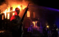 A St. Louis police officer stands guard as firefighters extinguish a fire in the 1300 block of Bayard Avenue on Wednesday, Aug. 19, 2015, after a fatal officer-involved shooting near Page Boulevard at Walton Avenue. Photo by Christian Gooden, cgooden@post-dispatch.com