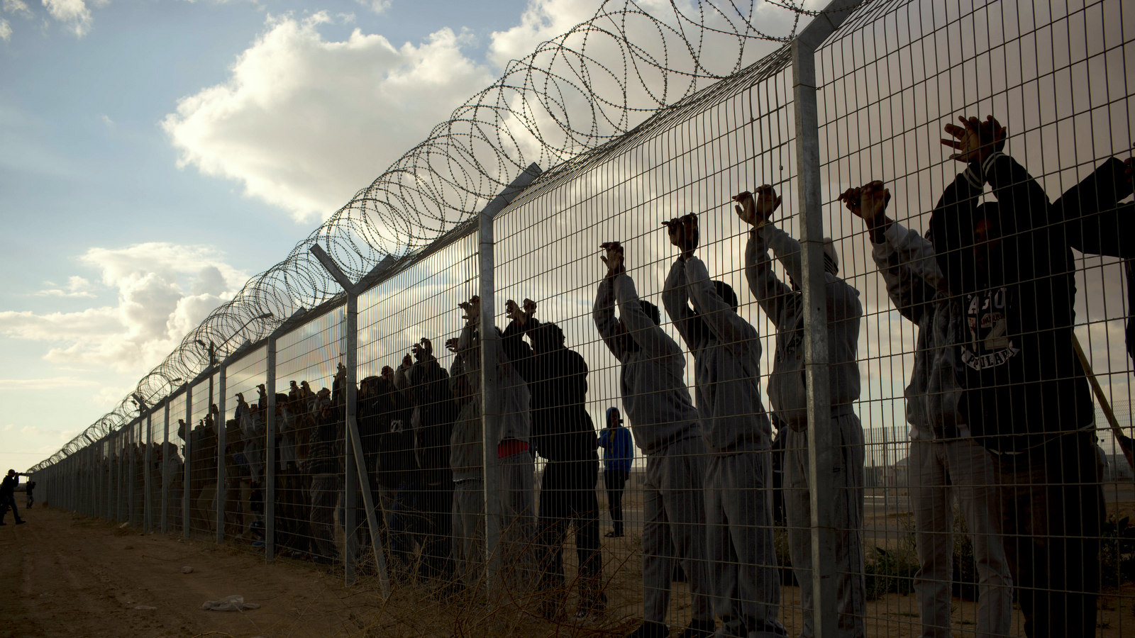 African migrants stands inside Holot detention center as others protest outside against the detention center near Ktsiot the Negev Desert in southern Israel, Monday, Feb. 17, 2014. (AP Photo/Oded Balilty)