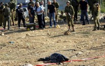 Israeli soldiers stand near the body of 27-year-old Palestinian Fadi Froukh, in the Beit Einun junction east of the West Bank city of Hebron, Sunday, Nov 1, 2015. (AP/Nasser Shiyoukhi)