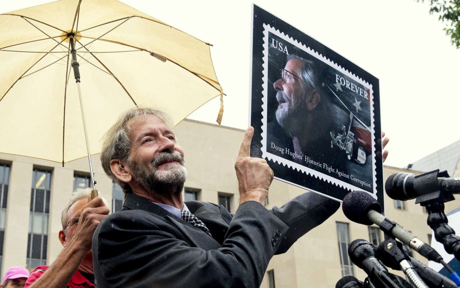 Douglas Hughes of Florida holds up a design for a stamp that was given to him by an artist as a gift, while meeting with reporters outside federal court in Washington, Thursday, May 21, 2015, . Hughes, who flew a gyrocopter through some of America's most restricted airspace before landing at the Capitol pleaded not guilty on Thursday to the six charges he faces. (AP Photo/Jacquelyn Martin)