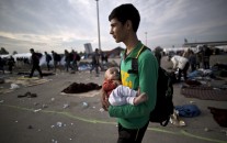 Afghan refugee Rasoul Nazari, 15, holds his 10-month-old nephew Imran after crossing the border between Hungary and Austria in Nickelsdorf, Austria. (AP Photo/Muhammed Muheisen)