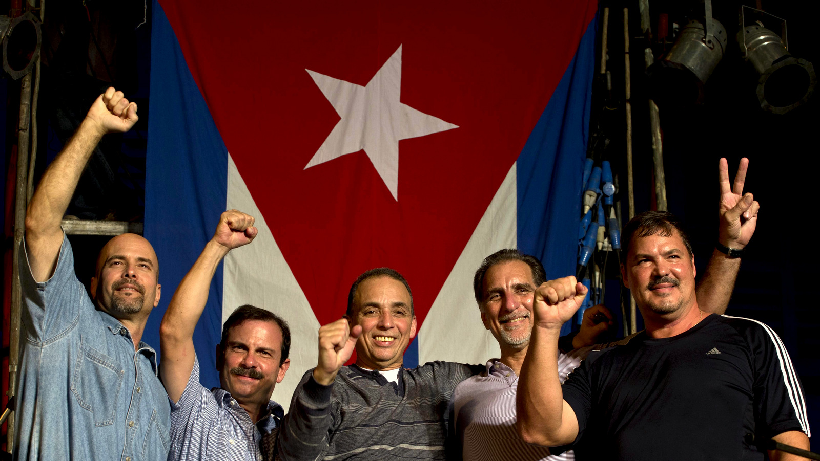  "The Cuban Five," from left, Gerardo Hernandez, Fernando Gonzalez, Antonio Guerrero, Rene Gonzalez and Ramon Labanino, wave to the public in front of a Cuban flag after a concert by Silvio Rodriguez in Havana, Cuba. Guerrero, Labanino, and Hernandez flew back to their homeland in a quiet exchange of imprisoned spies, part of a historic agreement to restore relations between the two long-hostile countries. Fernando and Rene had been previously released by the U.S. (AP Photo/Ramon Espinosa, File)