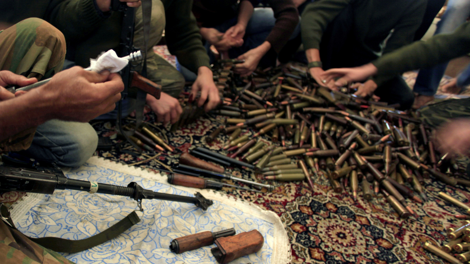 Free Syrian Army fighters clean their weapons and check ammunition at their base on the outskirts of Aleppo, Syria. (Khalil Hamra/AP)