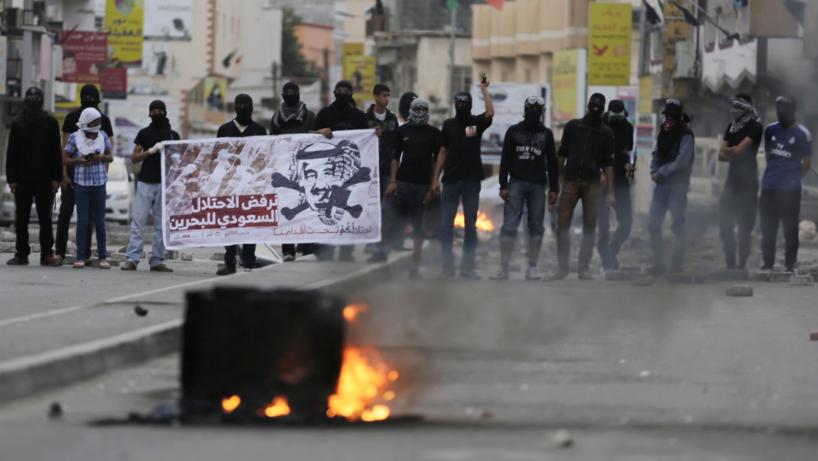 Bahraini anti-government protesters hold a banner with picture of Saudi king Salman, reading in Arabic, "We refuse Saudi occupation to Bahrain. Your occupation is under our feet," during clashes in Daih, Bahrain, Monday, March 14, 2016. Bahraini police detained a political activist and her year-old son on Monday in an operation that came on the fifth anniversary of Saudi and Emirati soldiers putting down Arab Spring-inspired protests in the tiny island kingdom. AP Photo/Hasan Jamali)
