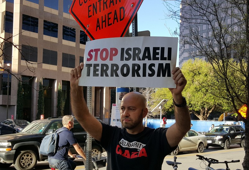 An activist holds a "Stop Israeli Terrorism" sign outside the JW Marriott hotel in Austin, Texas on March 14, 2016. Jewish Voice For Peace organized the protest against the Israeli ambassador's appearance on the SXSW panel, "Building The Perfect Country."