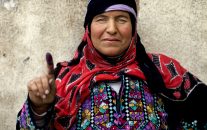 A Syrian woman poses for a photograph showing her inked finger after voting outside a polling station during the Syrian parliamentary election in Damascus, Syria, Wednesday, April 13, 2016. (AP Photo/Hassan Ammar)