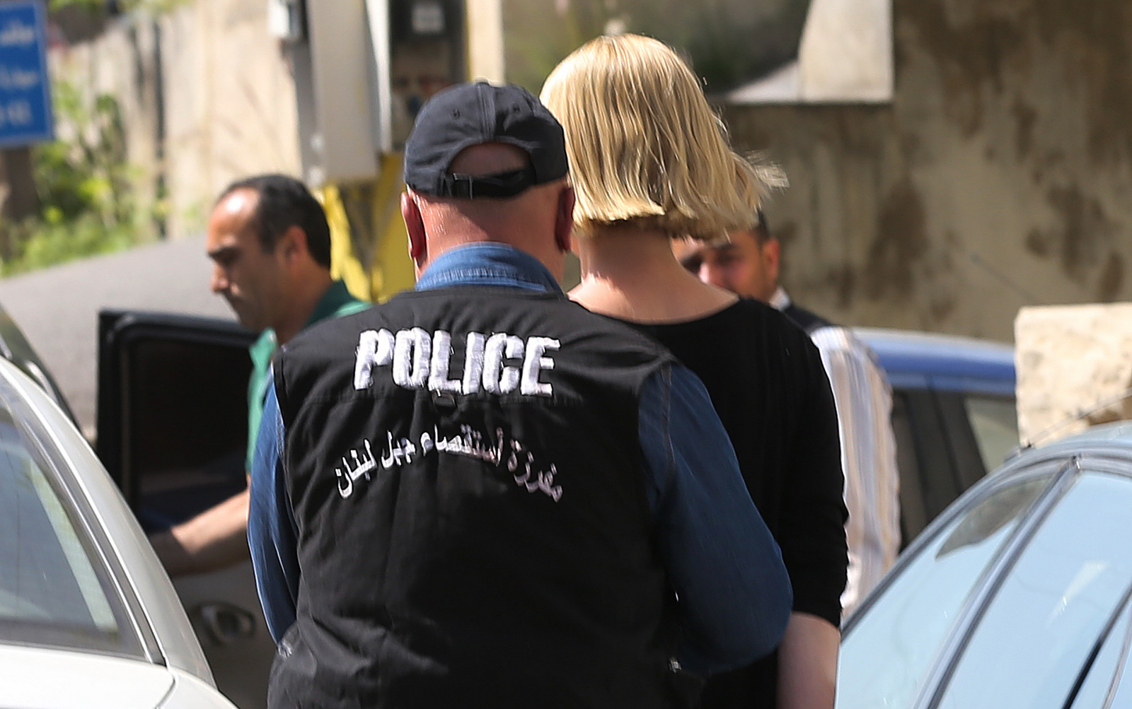 A Lebanese policeman escorts Australian TV presenter Tara Brown, who is seen handcuffed, as she is taken from a Lebanese courthouse where she was questioned by an investigative judge over suspicion of taking part in an abduction attempt of two Lebanese-Australian children, in Baabda, east of Beirut, Lebanon, Monday April, 18, 2016. (AP Photo/Hussein Malla)