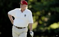 Donald Trump stands on the 14th fairway during a pro-am round of the AT&T National golf tournament at Congressional Country Club in Bethesda, Md.