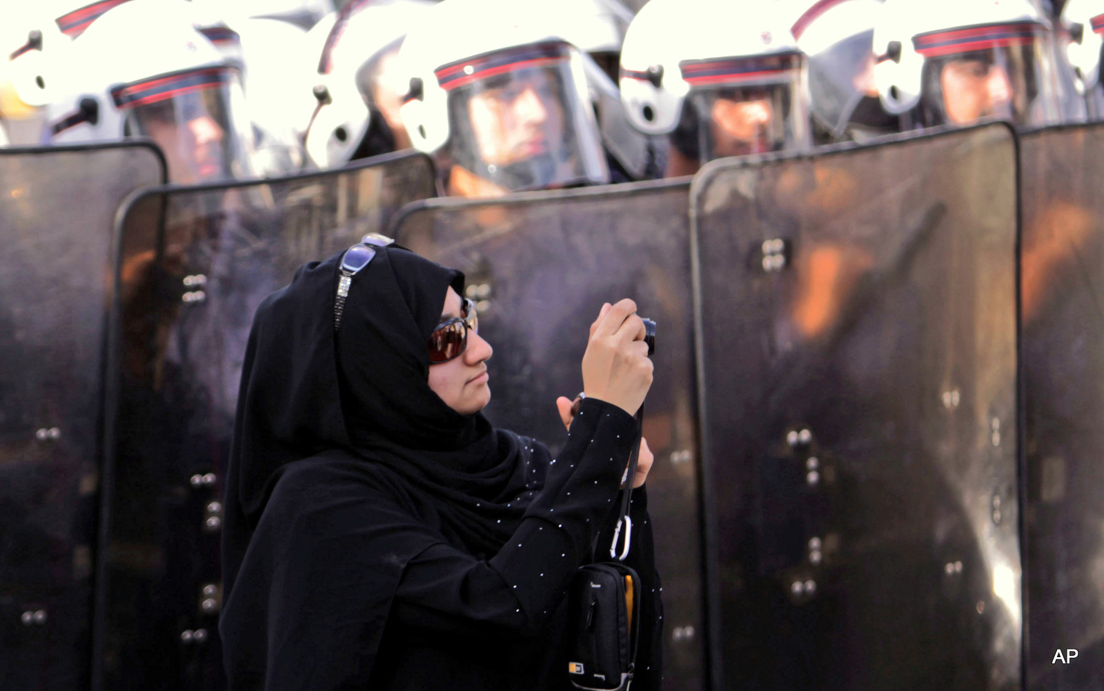 An anti-government protester stands in front of riot police while photographing other demonstrators in Manama, Bahrain. On Tuesday, June, 14, 2016, Bahrain said it has suspended all activities by Al-Wefaq, the largest Shiite opposition political group, and frozen its assets amid a widening crackdown on dissent, five years after the country’s Arab Spring protests.
