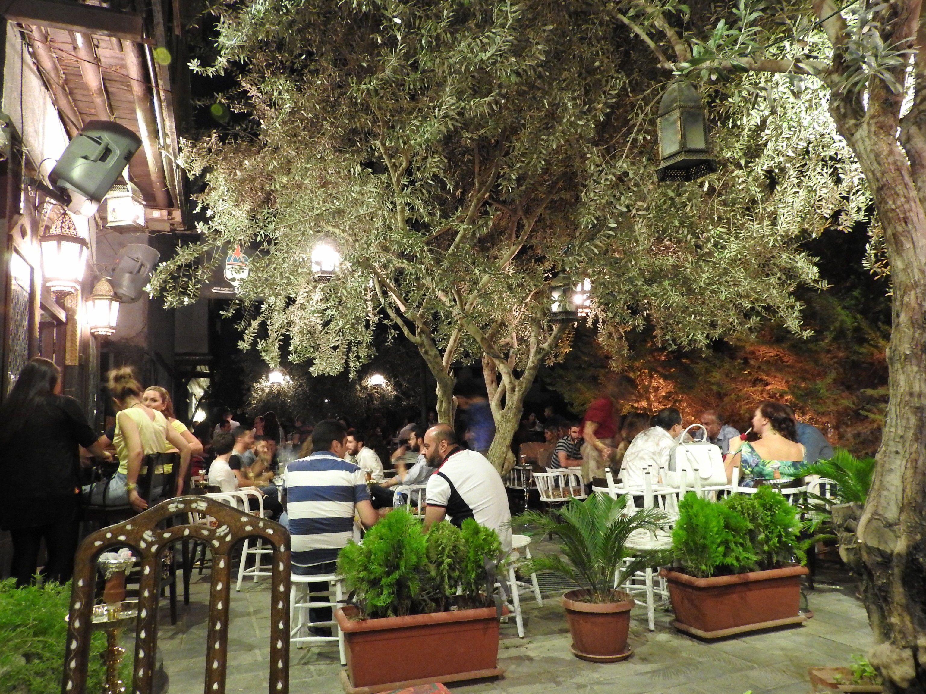 The Abu Zolouf bar is one among many bars and lounges opened in the East Gate quarter of the Old City in recent months. Two years ago, I sat with the adjacent restaurant owner, Nabil, outside his then-vacant restaurant discussing the frequent mortars that Jebhat al-Nusra and the Free Syrian Army were firing on Damascus, from Jobar, less than 1 km to the northeast. As mortars fell in nearby districts of the Old City, Nabil narrated close-calls he had had with such mortars hitting outside his restaurant. He also lamented the loss of customers in recent years. Since their May 30, 2016, opening, the Abu Zolouf bar has nightly from 70 to 150 patrons looking to relax outdoors.