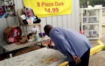 Arthur Baines signs "RIP Big Dogg" on a folding table that Alton Sterling used to sell homemade music CDs outside the convenience store, Wednesday, July 6, 2016, in Baton Rouge, La.