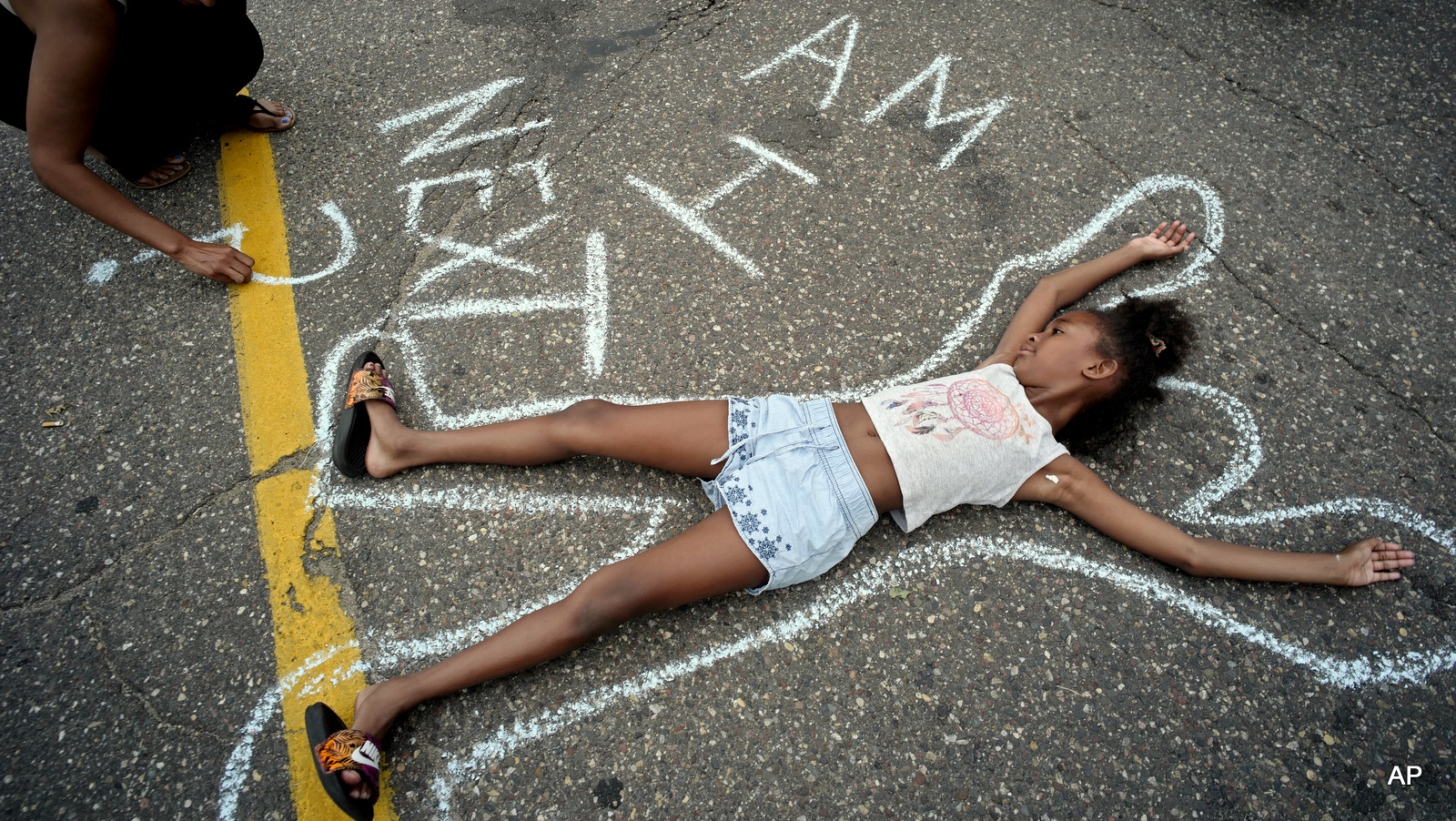 Tia Williams, left, and her daughter Aissa create a display on the street outside the Minnesota governor's official residence Thursday, July 7, 2016, in St. Paul, Minn., as people gathered to protest the shooting death of Philando Castile by police. 