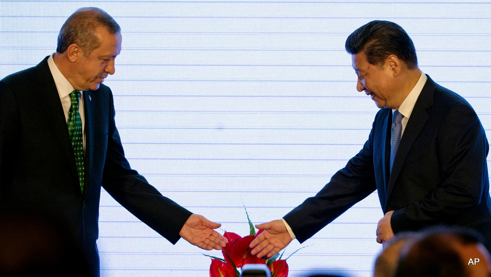 Chinese President Xi Jinping, right, and Turkey's President Recep Tayyip Erdogan, left, invite each other to sit as they attend the Turkey-China Business Forum at a hotel in Beijing, Thursday, July 30, 2015.