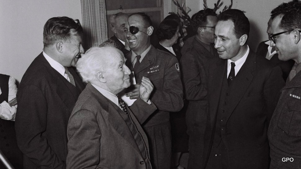 Prime Minister David Ben Gurion with his chief aide, Shimon Peres. In background: defense minister Moshe Dayan and Ben Gurion aide, Teddy Kollek.