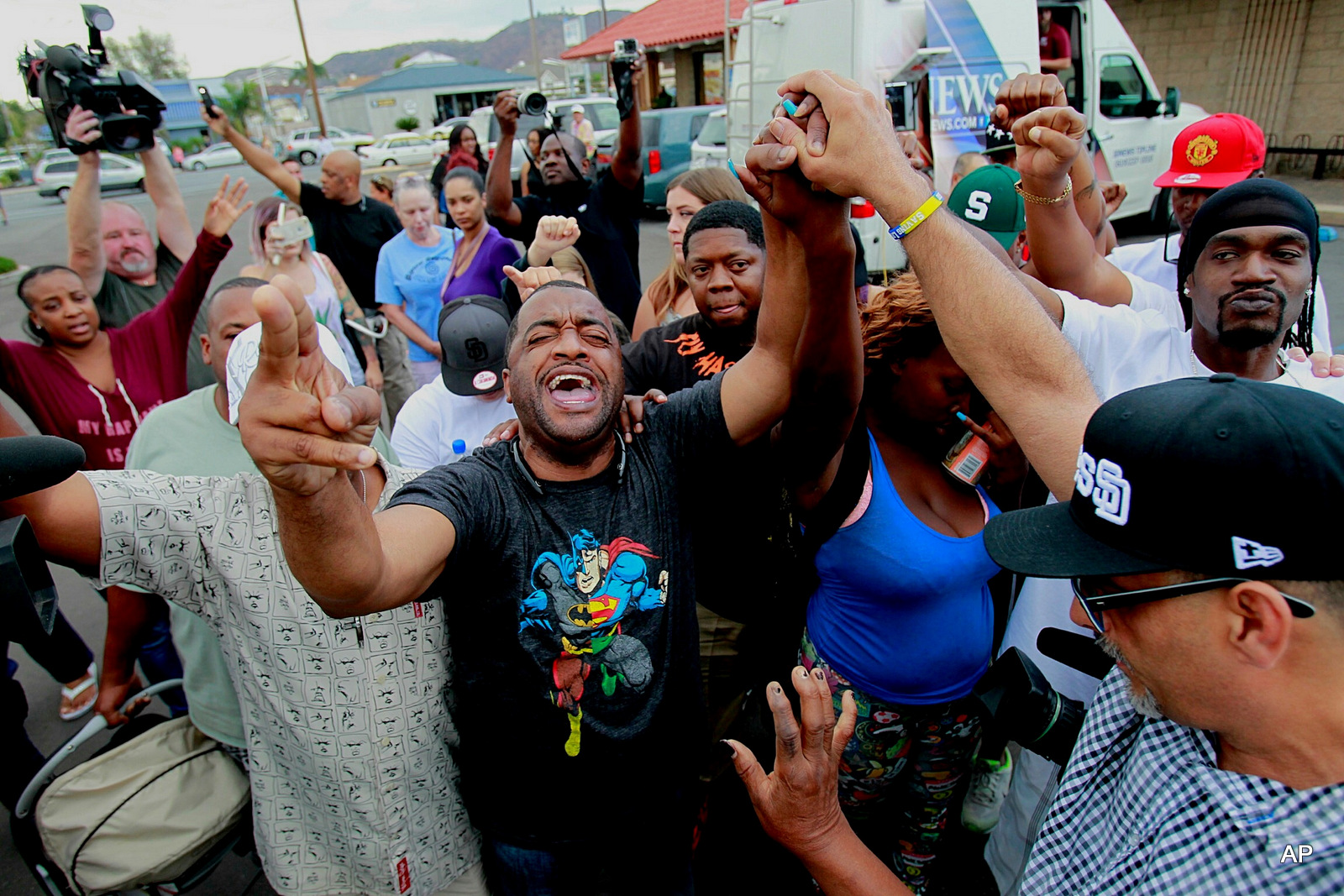 Pastor Russell Bowman, center, prays out loud as people gather at the scene where an African-American man was shot by police in El Cajon, east of San Diego, Calif., Tuesday, Sept. 27, 2016.