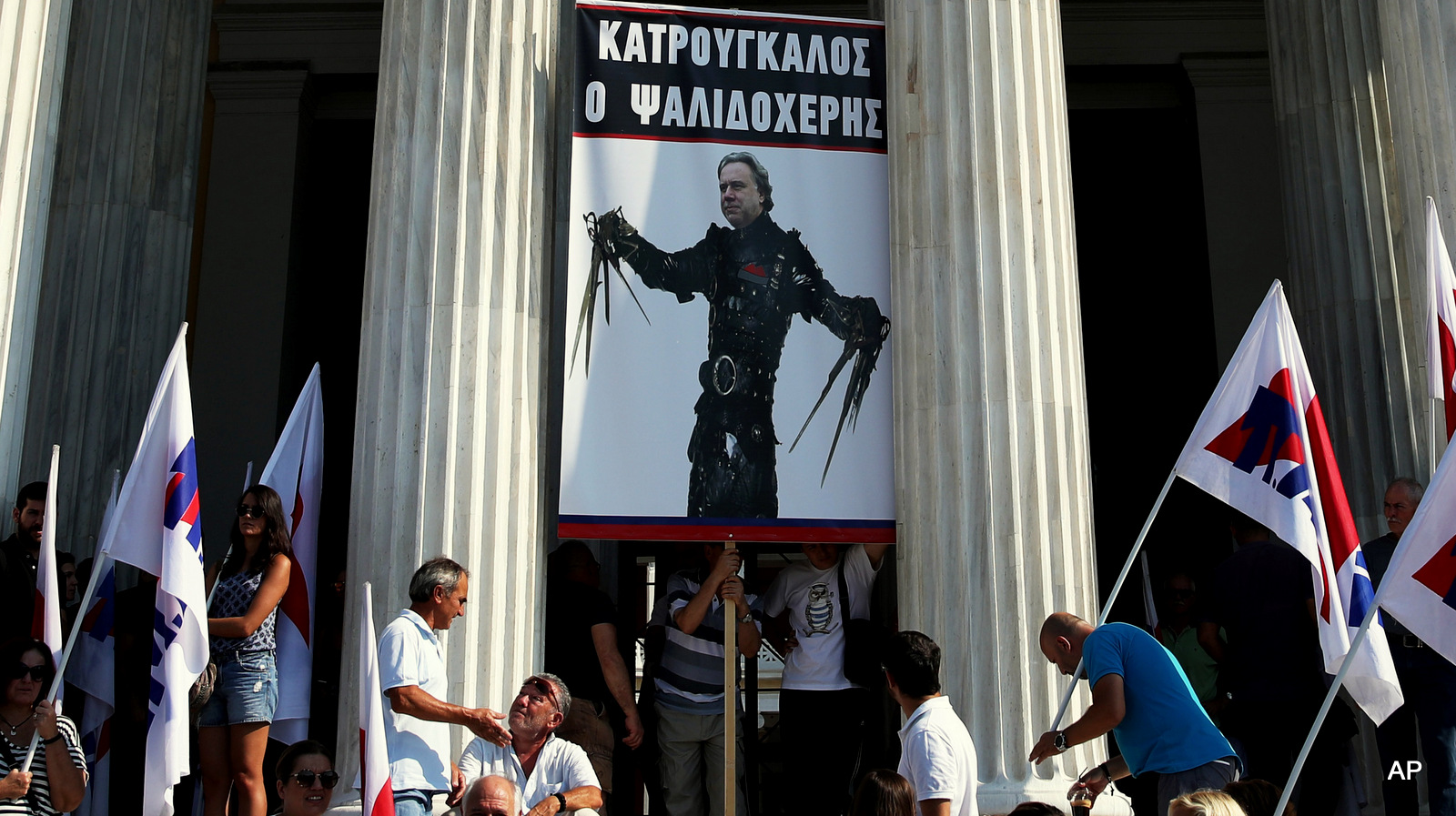 Protesters against new austerity measures hold a placard depicting Labour Minister George Katrougalos as the movie character Edward Scissorhands during a protest outside Zappeion Hall in Athens, Friday, Sept. 16, 2016. The placard reads in Greek"Katrougalos Scissorhands".