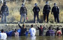 Dozens of protestors demonstrating against the expansion of the Dakota Access Pipeline wade in cold creek waters confronting local police, as remnants of pepper spray waft over the crowd near Cannon Ball, N.D., Wednesday, Nov. 2, 2016.