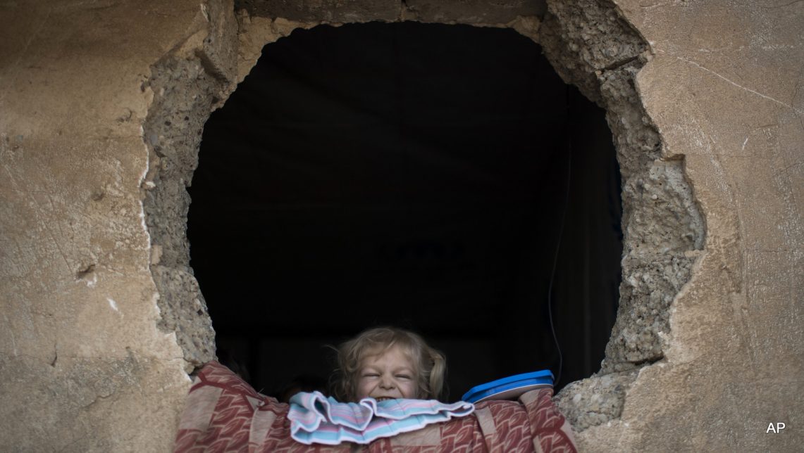 An Iraqi girl, who was displaced by fighting in Mosul, looks out of her window at a camp for internally displaced people, in Hassan Sham, east of Mosul, Iraq, Wednesday, Nov. 9, 2016. The United Nations says over 34,000 people have been displaced from Mosul, with about three quarters settled in camps and the rest in host communities.