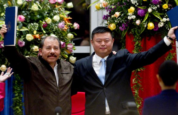 In this June 14, 2013 file photo, President Daniel Ortega, left, and Chinese businessman Wang Jing hold up a concession agreement for the construction of a multibillion-dollar canal at the Casa de los Pueblos in Managua. (AP Photo/Esteban Felix)