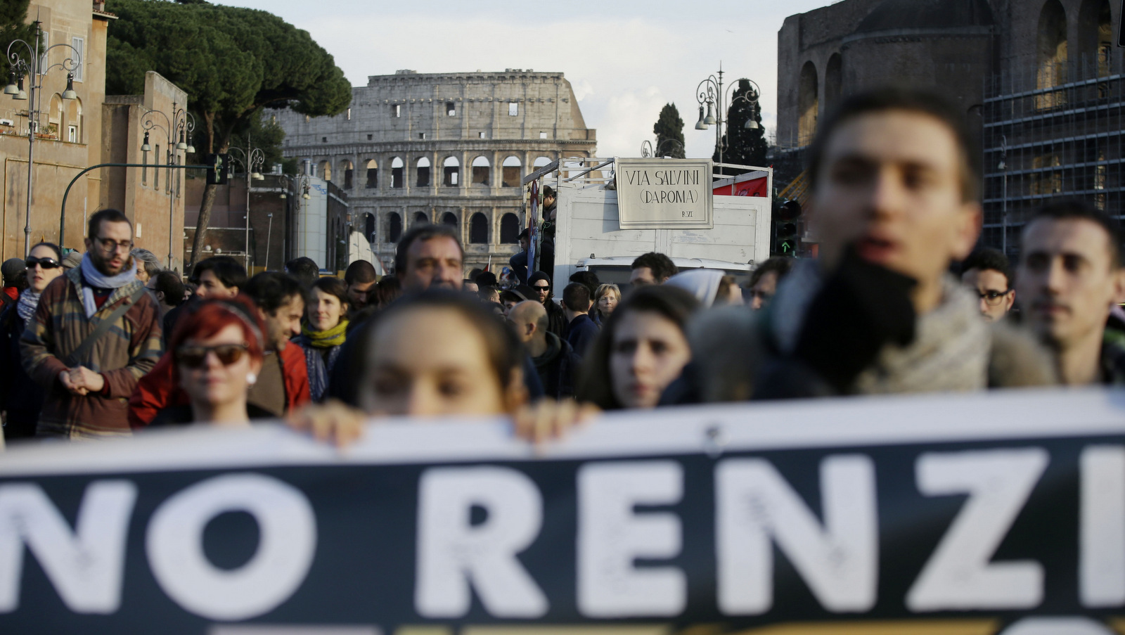 Demonstrators hold up a banner reading in Italian "No to austerity policies. No to Renzi's government. Never with Matteo Salvini, Rome does not want you" as another banner reading in Italian "Salvini go away from Rome" adorns a truck. Feb. 28, 2015. (AP/Gregorio Borgia)
