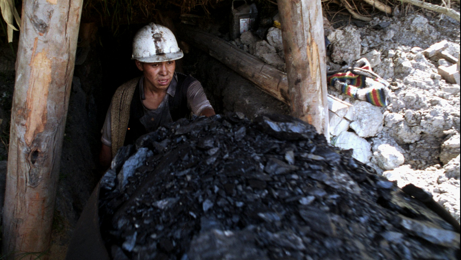 A coal worker pushes a cart full of the fuel out a mine in the central Colombian city of Topaga, in this February 1995 photo. (AP Photo/Fernando Llano/File)