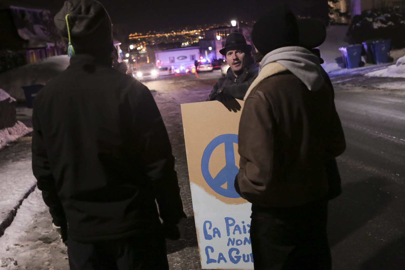 Martin St. Louis holds a sign that reads "la paix pas la guerre" (peace, not war) near a Quebec city mosque after a deadly shooting in Quebec City, Canada, Sunday, Jan. 29, 2017. Quebec Premier Philippe Couillard termed the act "barbaric violence" and expressed solidarity with victims' families. (Francis Vachon/The Canadian Press via AP)