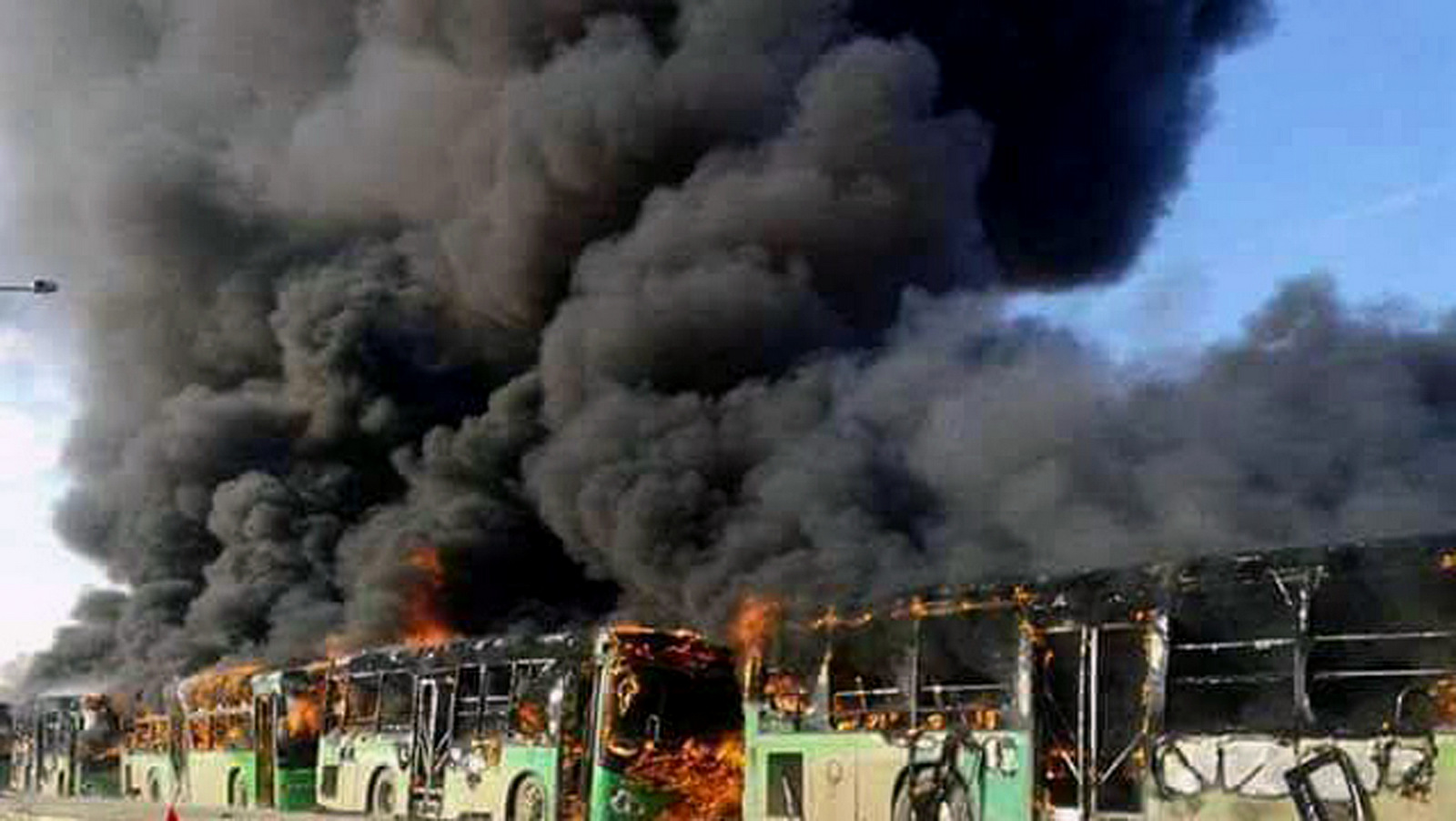 Smoke rises from buses transporting fleeing civilians after Syrian rebels burned at least five buses assigned to evacuate the wounded and sick from two villages in northern Syria. Dec. 18, 2016. (SANA via AP)