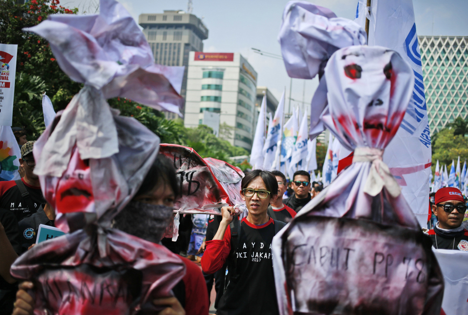 Workers carry a mock coffin and effigies during a May Day rally in Jakarta, Indonesia, Monday, May 1, 2017. Thousands of workers attended the rally urging the government to raise minimum wages, ban outsourcing practices, provide free health care and improve working condition for workers in the country.