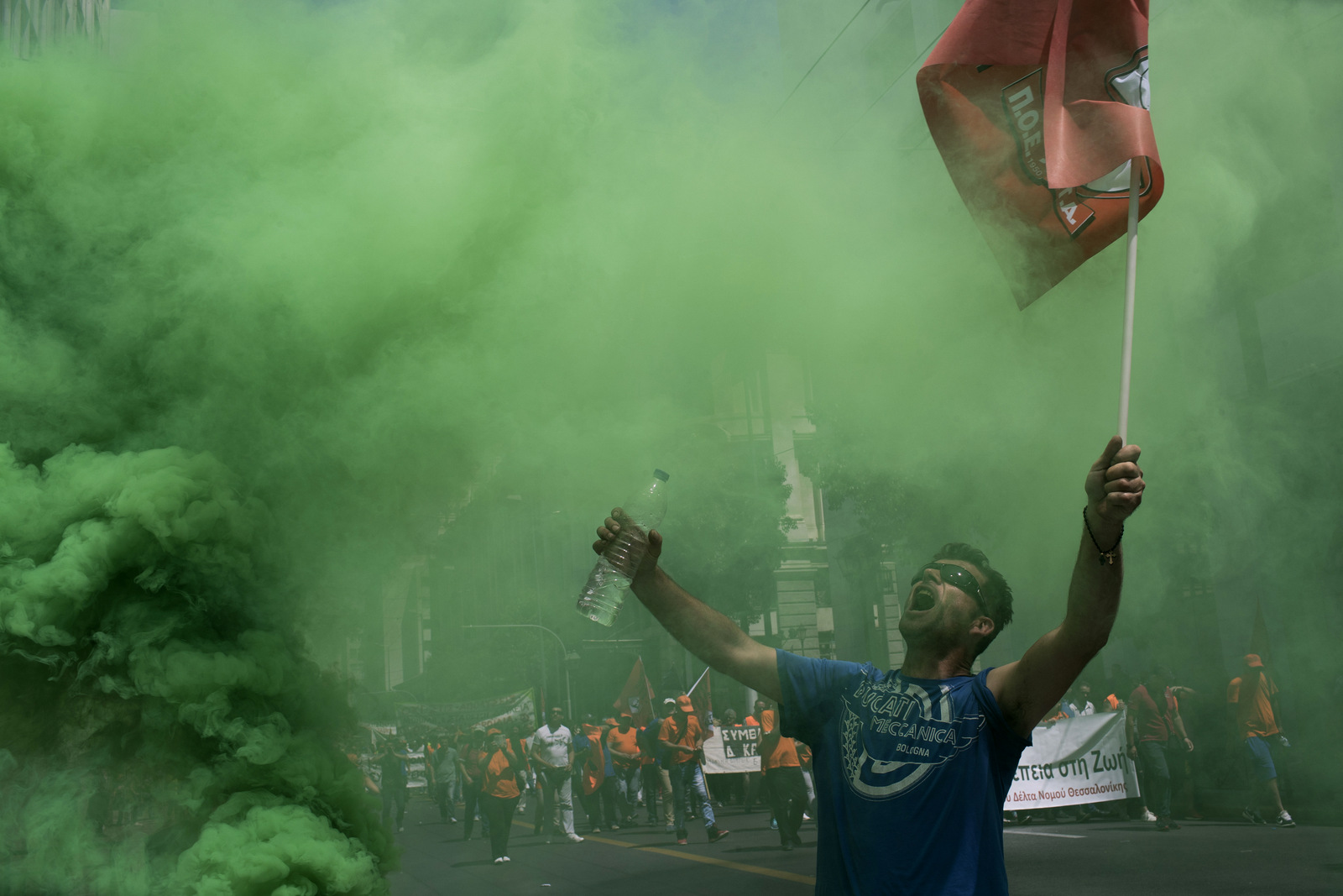 A protester reacts next to a flare outside the the Interior Ministry as thousands of striking municipal workers demonstrate in central Athens, June 22, 2017. Union officials want the left-led government to grant full-time, permanent state jobs to municipal workers employed on short-term contracts that have expired or are about to expire. (AP/Petros Giannakouris)