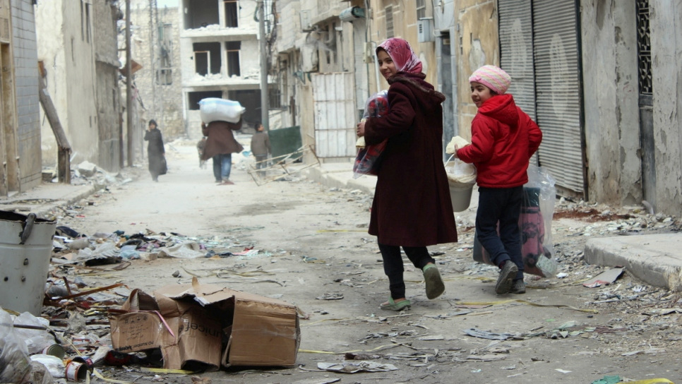 In the badly damaged Al-Shaar neighbourhood in East Aleppo, returnee families and displaced residents receive UNHCR relief assistance at a distribution point run by the Al Ihsan charity in March, 2017. (Photo: UNHCR/Hameed Marouf)