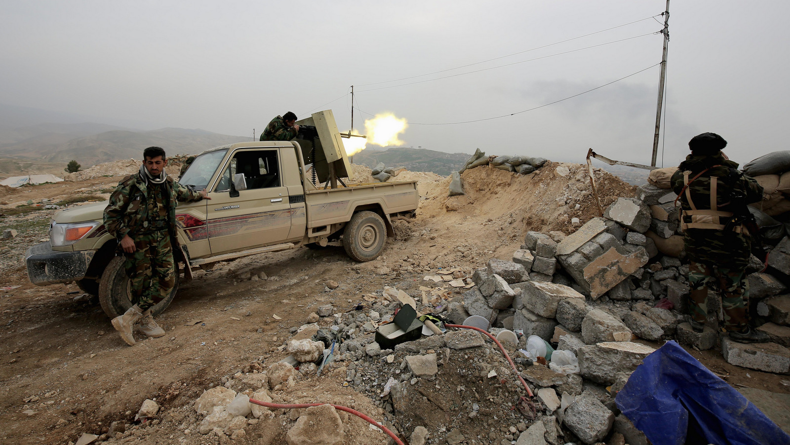 Well-armed Kurdish Peshmerga fighters fire a weapon toward the strategic town of Sinjar, northern Iraq. . (AP/Bram Janssen)