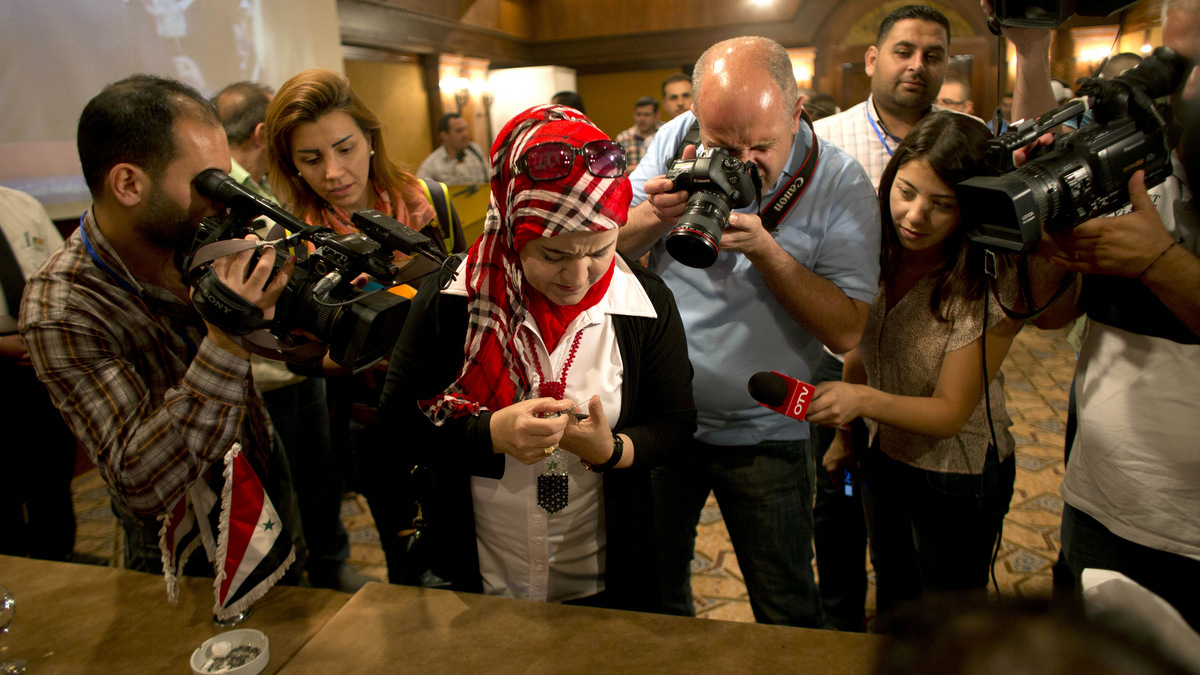 Firyal Sheikh El-Zour, 50, draws blood from her thumb with a syringe to use to mark a ballot, in Damascus, Syria, June 3, 2014. (AP/Dusan Vranic)