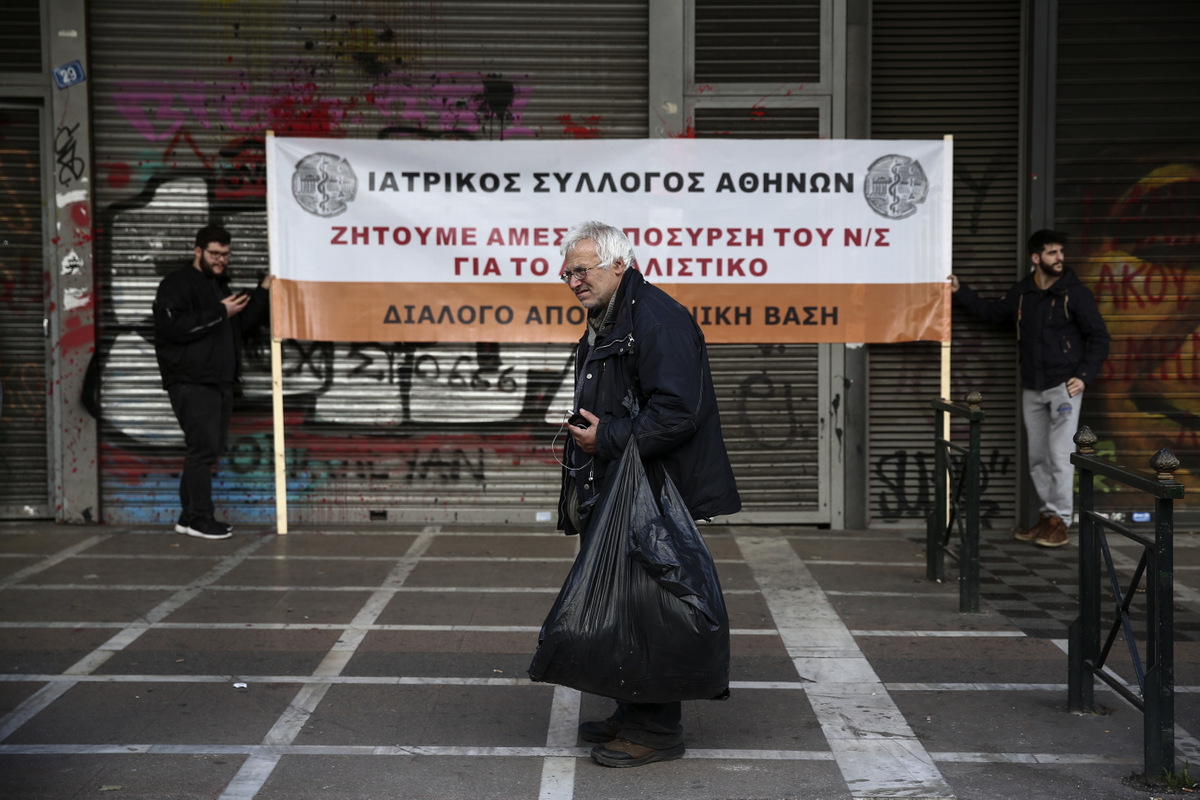 A man stands in front of a banner during an anti-austerity rally by workers in the health sector outside the Labour ministry in Athens, March 2, 2017. Monitors from Greece's European Union creditors and the International Monetary Fund re-launched talks in Athens on Tuesday on the country's stumbling bailout program. The banner reads : "Medical Association of Athens, We demand the immediate withdraw of the pension bill". (AP/Yorgos Karahalis)