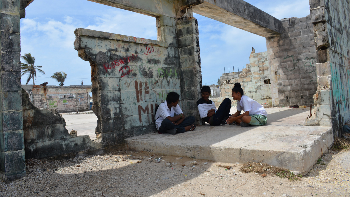 High school students hang out in the shell of a former hospital on Ebeye, steps from the ocean. Marshall Islands, 2015. (Photo: Dan Zak)