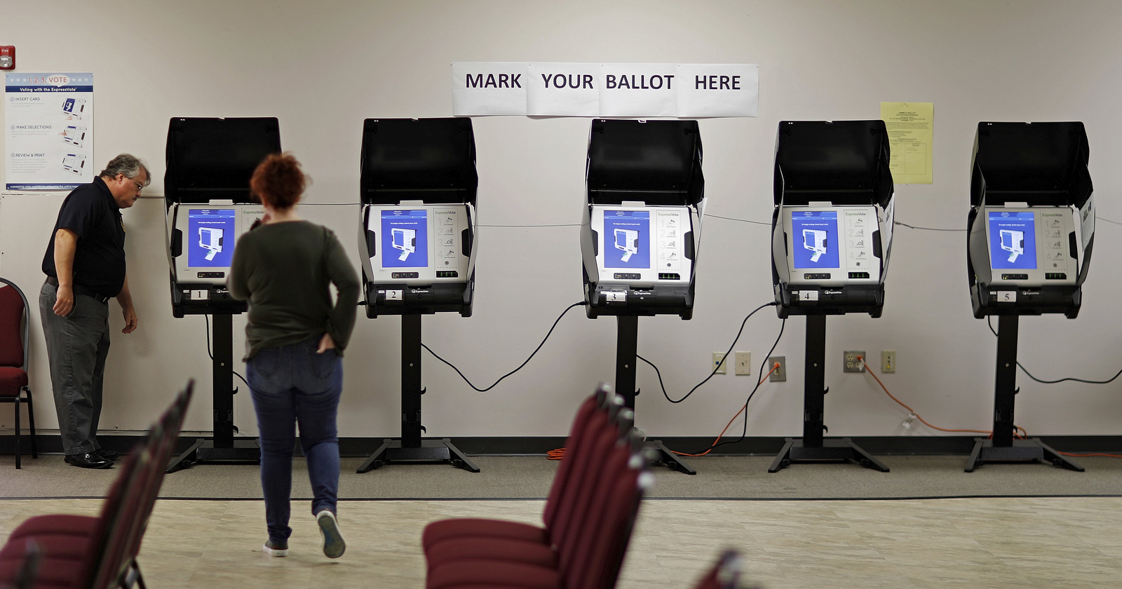 Kelly Monroe, investigator with the Georgia secretary of state office, left, takes a look at a new voting machine being tested at a polling site in Conyers, Ga. Last summer, a security expert came across a gaping hole in Georgia's election management system. The revelation prompted a lawsuit seeking to compel Georgia to toss all of its touchscreen voting machines and replace them with a system that provides a paper record of every ballot cast. Georgia is one of five states where no such record exists. Oct. 19, 2017 (AP/David Goldman)
