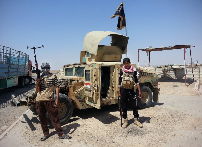, 2014 file photo, Islamic State group militants stand with a captured Iraqi Army Humvee at a checkpoint outside Beiji refinery, some 250 kilometers (155 miles) north of Baghdad, Iraq.