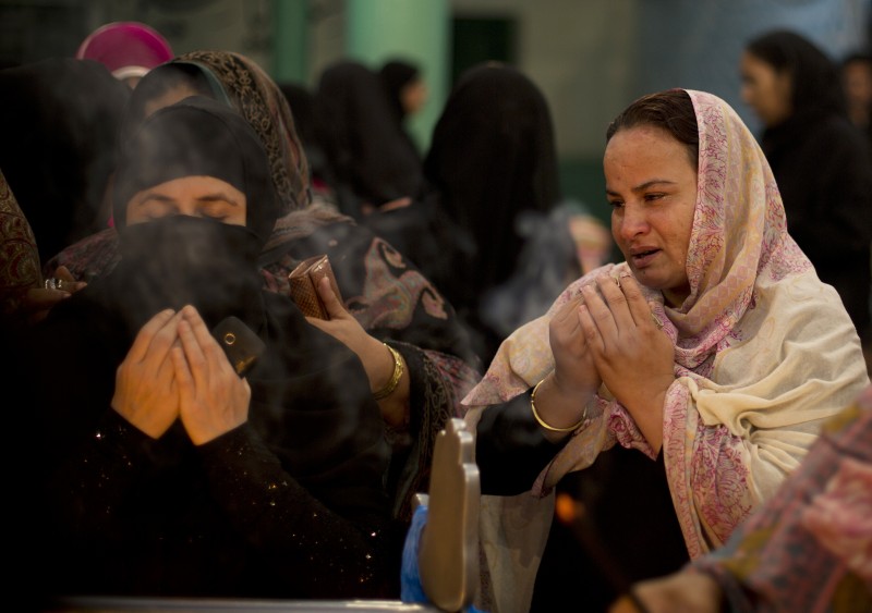 Women pray dressed in a hijab and another in a niqab. 