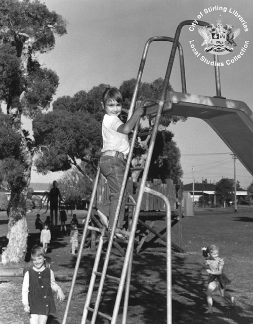 A is photographed climbing a slide. Around him children play. Slenderman stands in the background under a tree, reaching for other children.