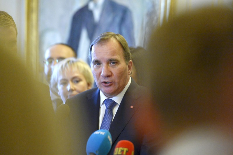 The Swedish Prime Minister speaks at a microphone at a crowded press conference.